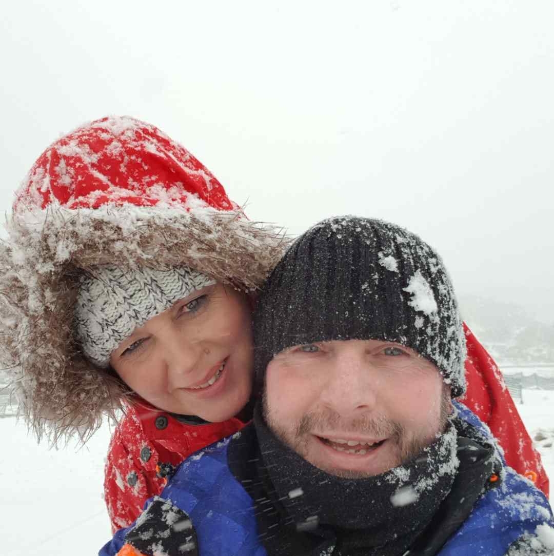 Anu and her husband smiling together in the snow